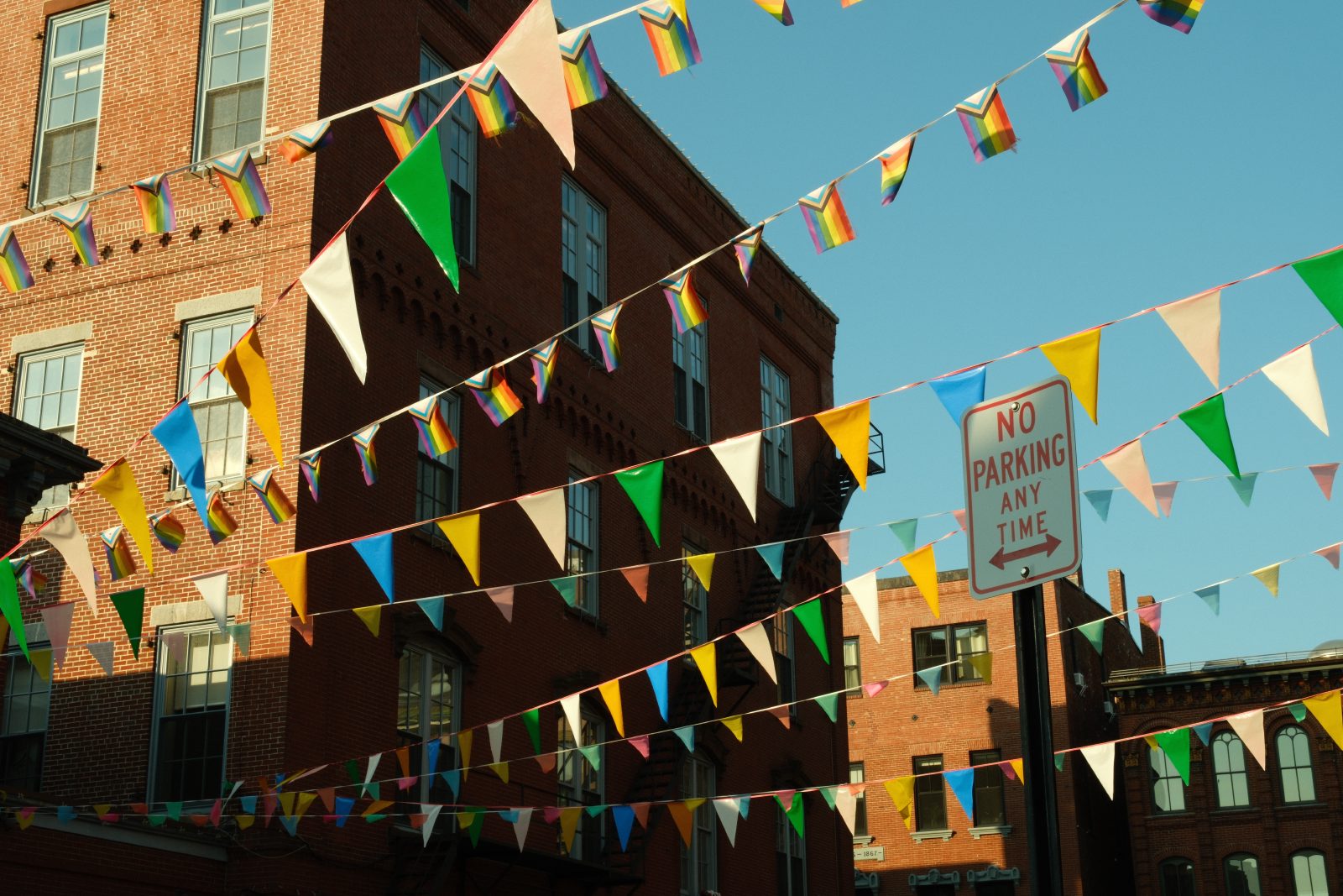 A rainpipe running down the side of a brick building covered in graffiti and stickers