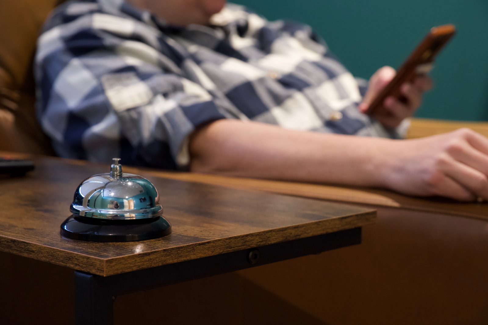 A silver call bell in the foreground with a woman's arm in the background