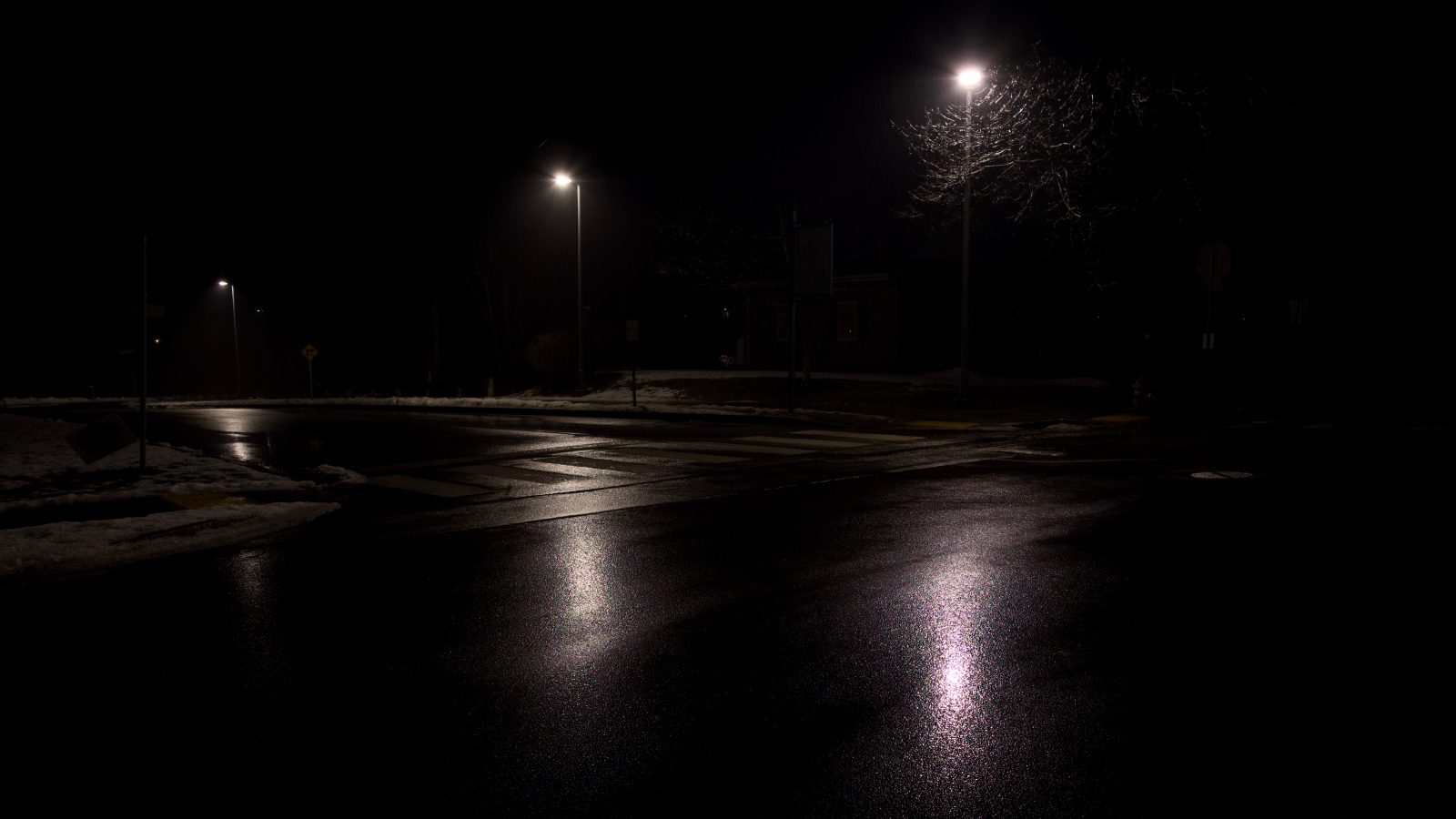 A wet and cold night with three street lights illuminating the barren scene.