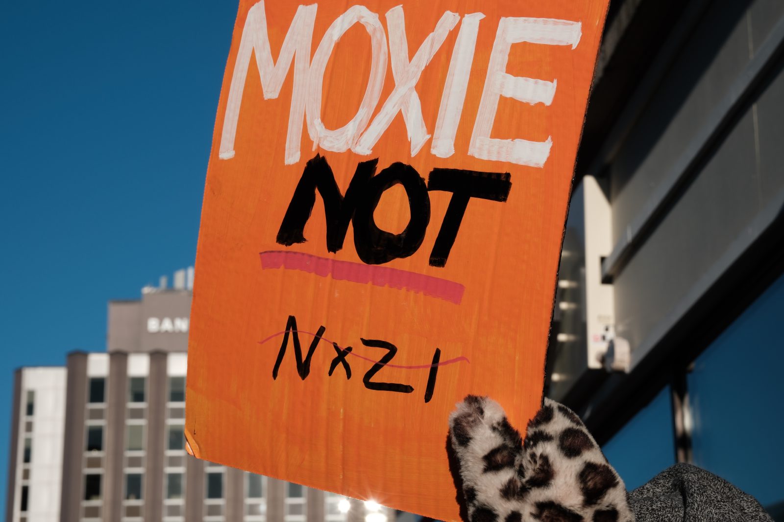 A protest sign in orange reading Moxie Not Nazis.